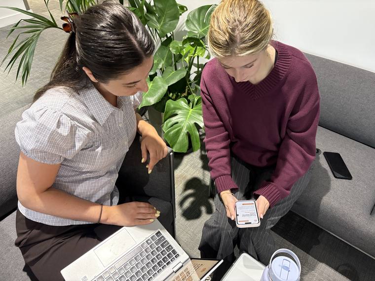 A colleague using the Carus portal on a laptop while another reviews it on a phone.